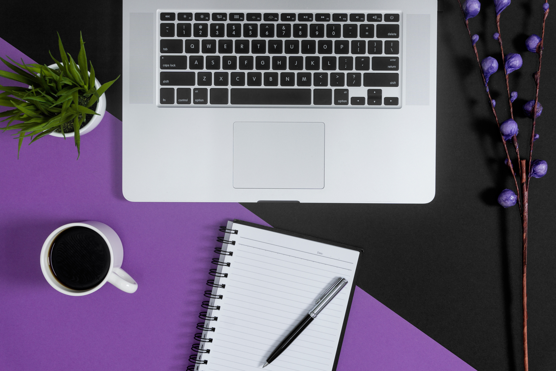 Laptop and notebooks on purple and black background.